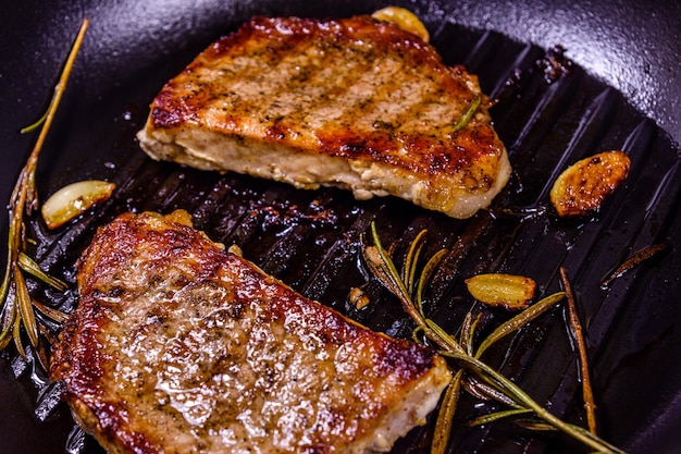 Bistecche arrosto con aglio rosmarino e spezie in una padella in ghisa