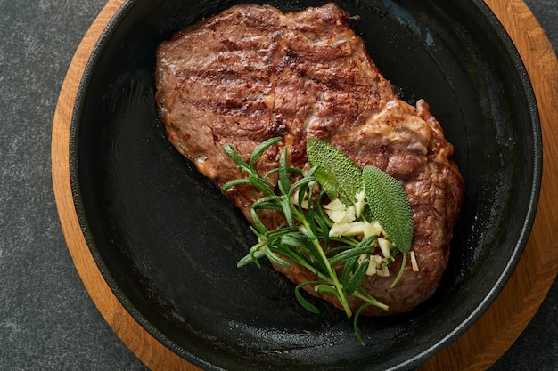 Bistecche Bistecca di carne alla griglia affettata New York o Ribeye con spezie rosmarino e pepe in padella di ferro nero su tavola di marmo su sfondo di legno vecchio Vista dall'alto Mock up