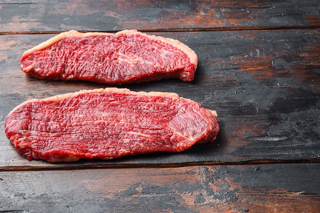 Bistecche di carne di manzo organica picanha, su fondo di legno vecchio scuro, spazio di vista laterale per testo.