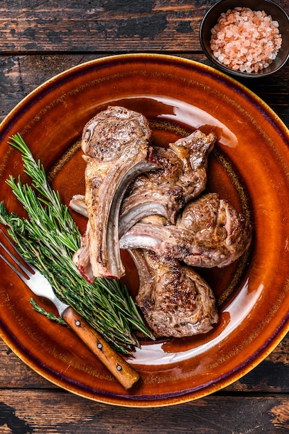 Bistecche di carne di montone di agnello alla griglia barbecue su un piatto. Fondo in legno scuro. Vista dall'alto.