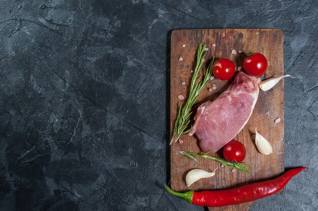 Bistecche di maiale sul tagliere con erbe e spezie