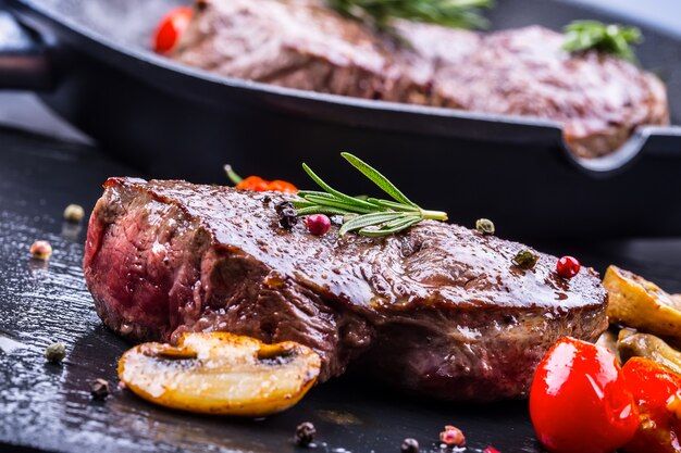 Bistecche di manzo alla griglia con funghi pomodori ed erbe aromatiche.