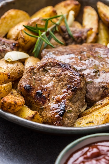 Bistecche di manzo alla griglia con salsa barbecue, patate arrosto e rosmarino.