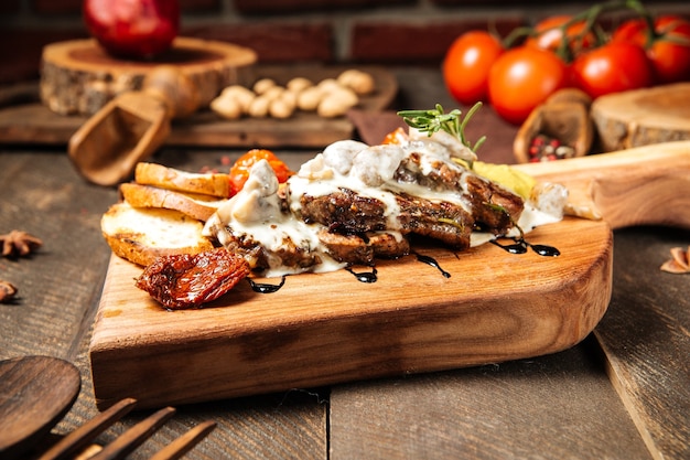 Bistecche di manzo alla griglia con salsa cremosa con verdure sulla tavola di legno