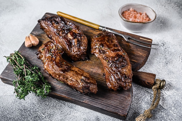 Bistecche di petto alla griglia in salsa barbecue su una tavola di legno su bianco. Vista dall'alto.