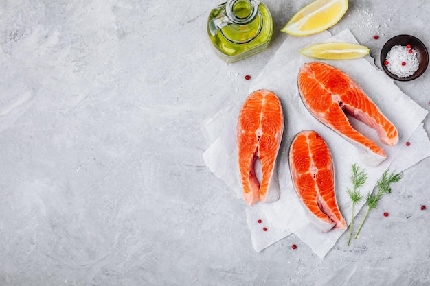 Bistecche di salmone crudo fresco con limone e aneto per la cottura su sfondo grigio Spazio per la copia della vista dall'alto