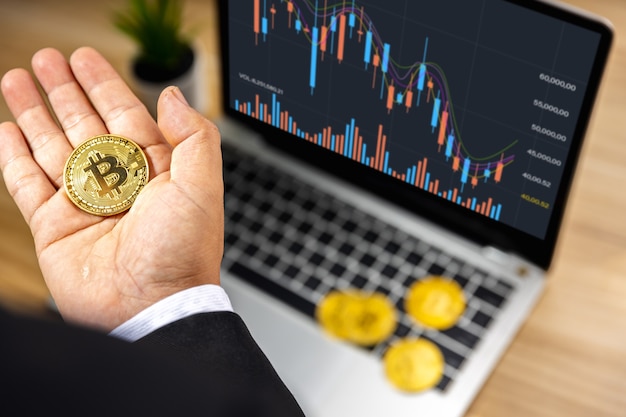 Bitcoin aziendale a disposizione dell'investitore con grafico grafico su laptop su tavolo di legno, mercato azionario e concetto di finanza forex