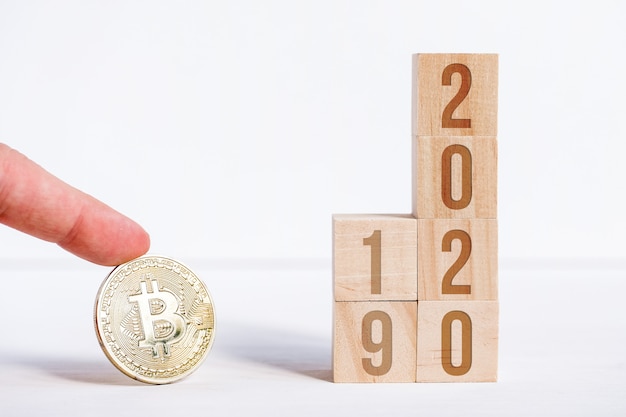 Bitcoin con numeri e 2019 sui cubi su un fondo di legno bianco.