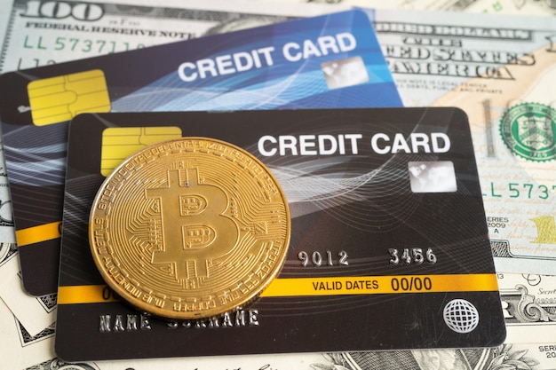 Bitcoin d'oro con carta di credito su banconote in dollari statunitensi per lo scambio elettronico in tutto il mondo