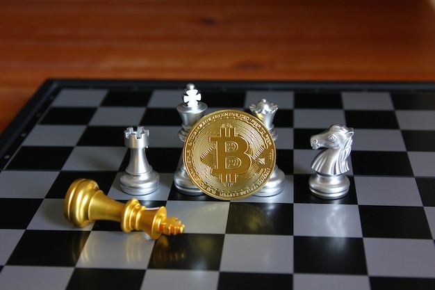 Bitcoin davanti a pezzi degli scacchi d'argento con scacchi del re d'oro giacciono sulla scacchiera concetto di idea di strategia bitcoin