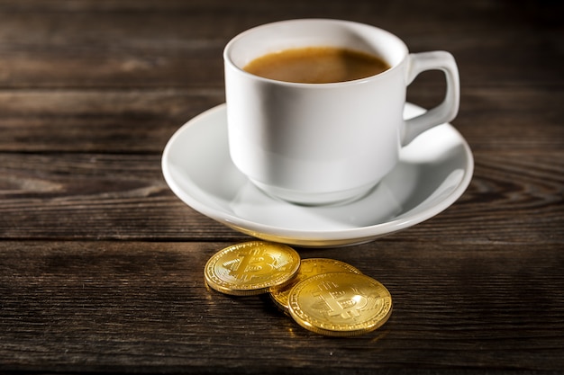 Bitcoin dorato di criptovaluta che sta sulla tazza di caffè isolata