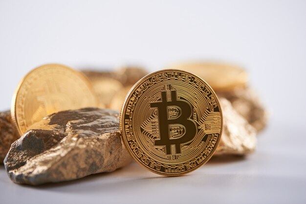 Bitcoin dorato lucido accanto a grumi d'oro