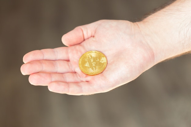 Bitcoin dorato nella mano di un uomo