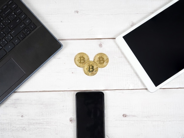 Bitcoin dorato sulla scrivania con tablet portatile e smartphone intorno al concetto di denaro digitale con vista dall'alto