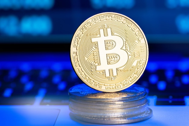 Bitcoin dorato sulla tastiera su sfondo grafico blu digitale Denaro virtuale Trading finanziario Criptovalute ed e-commerce