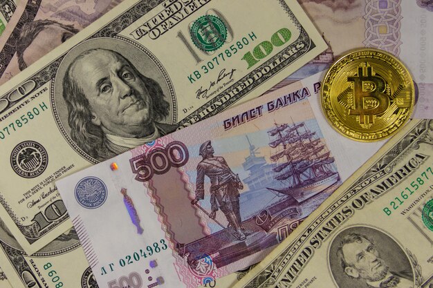 Bitcoin dorato sullo sfondo di dollari americani e rubli russi