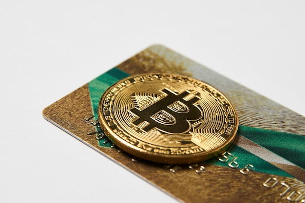 Bitcoin e carta di credito, primo piano. Carta di credito dorata e moneta bitcoin come concetto di metodo di pagamento