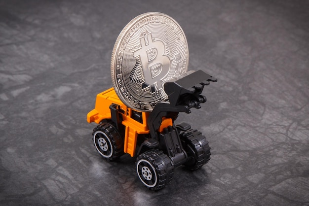 Bitcoin ed escavatore in miniatura simbolo di denaro virtuale elettronico e criptovaluta mineraria