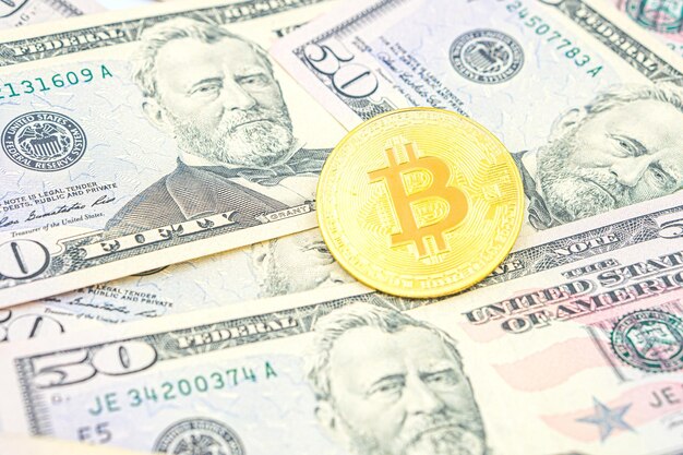 Bitcoin in cima alle banconote del dollaro degli Stati Uniti Bitcoin cash BTC criptovaluta raffigurata come una moneta d'oro d'oro che giace sopra dollari denaro reale degli Stati Uniti 50 dollari banconota di cinquanta dollari degli Stati Uniti.