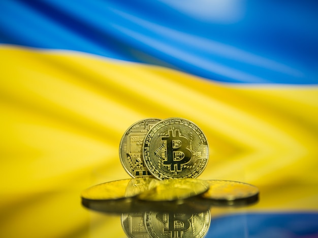 Bitcoin moneta d'oro e defocused bandiera dell'Ucraina sfondo. Concetto di criptovaluta virtuale.