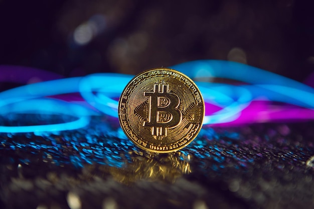 Bitcoin moneta di ferro d'oro su sfondo argento lucido. filo blu e rosa cyberpunk in futuro