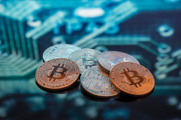Bitcoin monete d'oro, argento e rame e sfondo sfocato del circuito stampato. Concetto di criptovaluta virtuale.