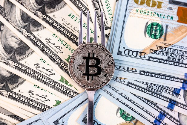 Bitcoin platino sullo sfondo di banconote da cento dollari