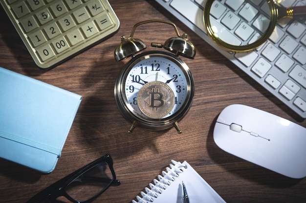 Bitcoin sull'orologio con una calcolatrice e altri oggetti sul tavolo di legno