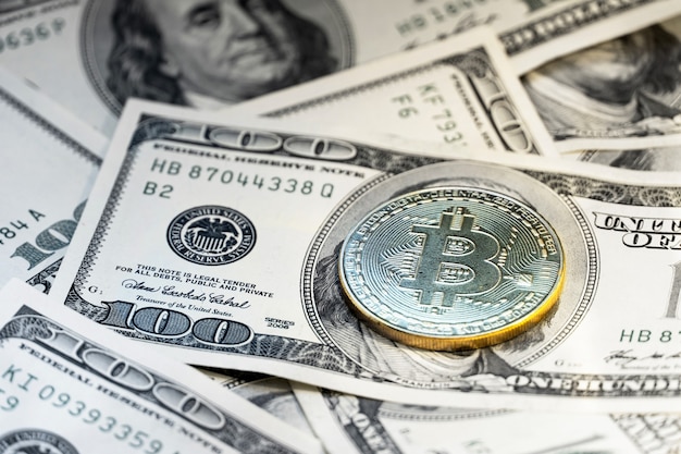 Bitcoin sullo sfondo di 100 fatture del dollaro.