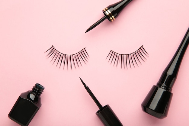 Black eyelashes and mascara on pink background with copy space. Beauty concept