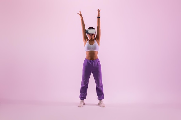 Black lady che sperimenta il fitness della realtà virtuale in cuffia vr facendo esercizio su sfondo di luce al neon rosa metaverse