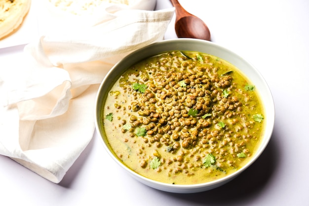 Black Masoor Dal fry o Dhaba Style Sabut Red Lentil dhal tadka al curry verde, servito in una ciotola. messa a fuoco selettiva