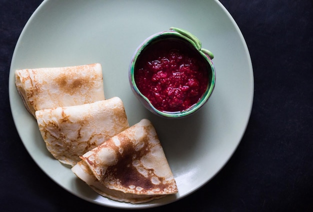 Blini triangoli o crepes nel piatto con marmellata di lamponi