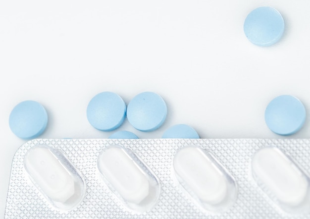 Blister con pillole bianche su pillole blu sparse Vista dall'alto