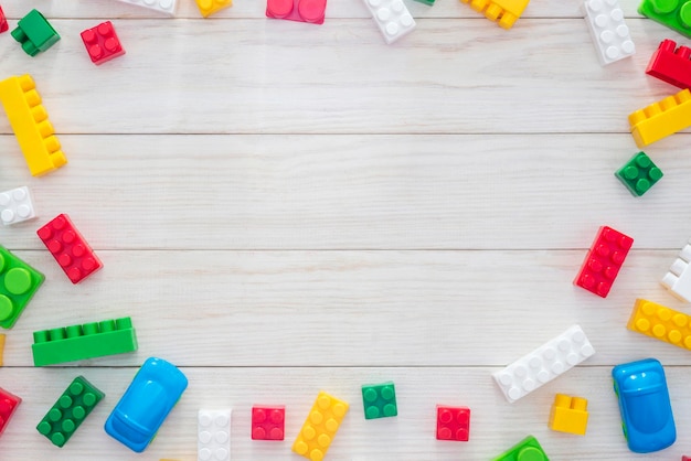 Blocchi di costruzione in plastica colorata su fondo di legno bianco