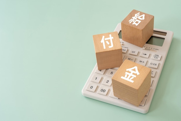 Blocchi di legno con testo concettuale kyufukin e una calcolatrice
