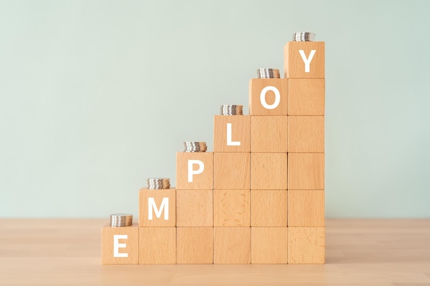 Blocchi di legno con testo EMPLOY di concetto e monete.