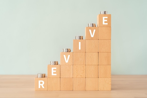 Blocchi di legno con testo REVIVE del concetto e monete.