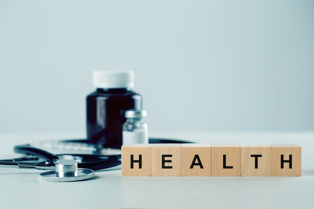 Blocco cubo di legno con parola salute e attrezzature mediche sul tavolo. concetto di assicurazione e assistenza sanitaria