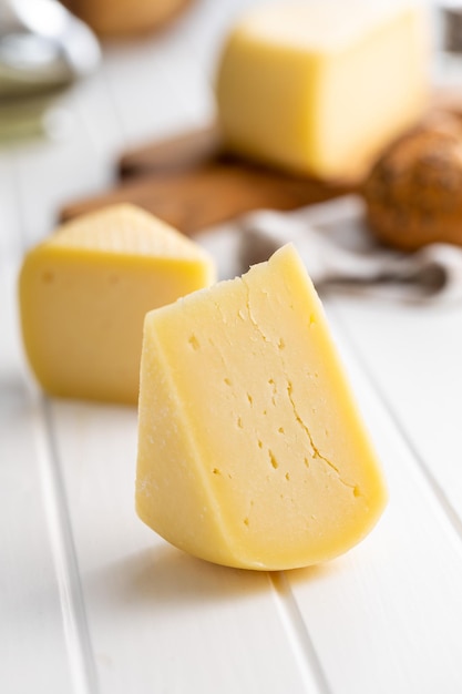 Blocco di formaggio a pasta dura Formaggio a fette sul tavolo bianco