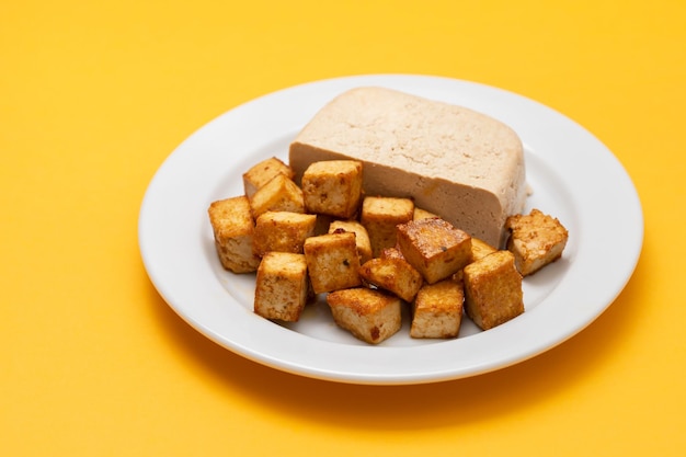 Blocco di tofu crudo su piattino bianco su giallo