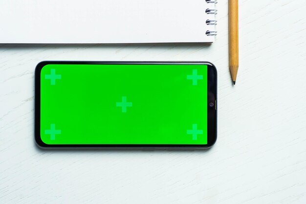 Blocco note bianco bianco smartphone mockup schermo verde e matita piatta Tamplate per il design