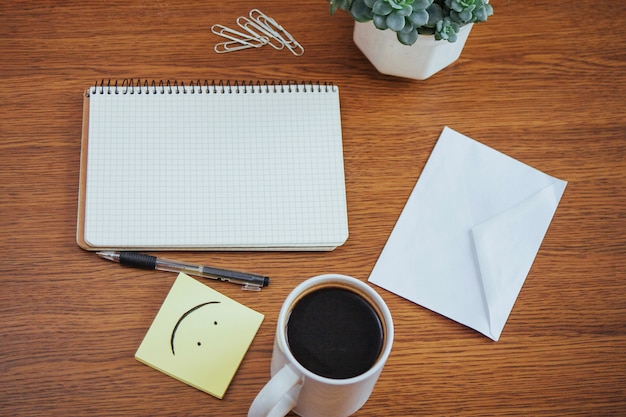 Blocco note e penna accanto ad una tazza di caffè su una tavola di legno all'aperto ad un caffè.