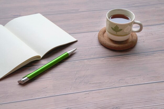 Blocco note e penna aperti del caffè sulla tavola di legno