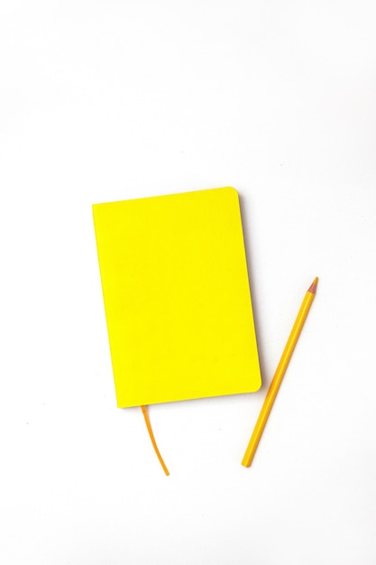 Blocco note giallo con matite colorate su uno sfondo bianco