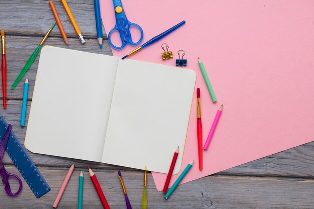 Blocco note in bianco e forniture d'arte per bambini su uno sfondo di legno