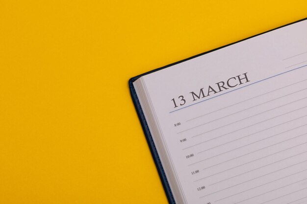 Blocco note o diario con la data esatta su sfondo giallo Calendario per il 13 marzo in primavera