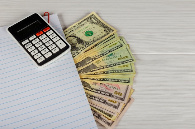 blocco note, soldi e calcolatrice sul tavolo di legno.