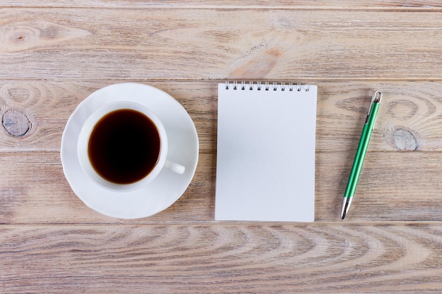 Blocco note vuoto e matita con una tazza di caffè sullo sfondo del tavolo in legno dell'ufficio Concetto di business con spazio di copia per qualsiasi desing