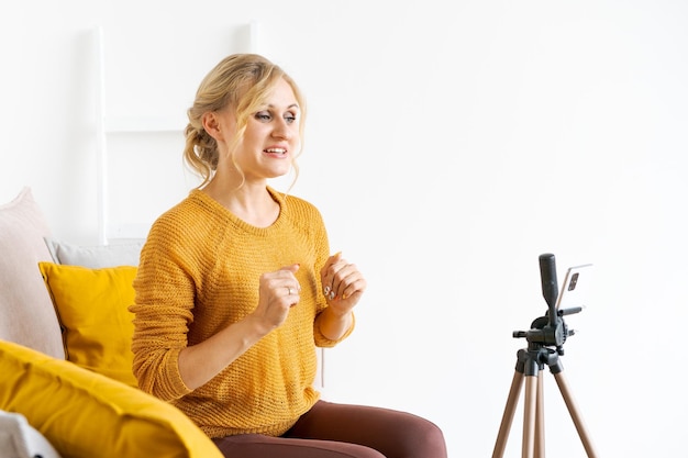 Blogger caucasico Donna che utilizza lo smartphone per registrare video online in soggiorno